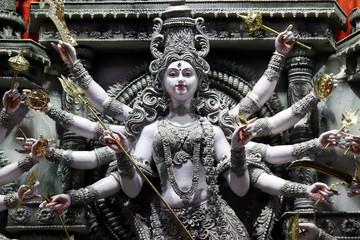 Goddess Durga idol at decorated Durga Puja pandal, shot at colored light, at Kolkata, West Bengal,...