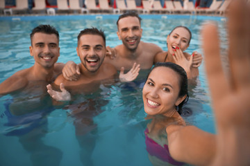 Happy young friends taking selfie in swimming pool