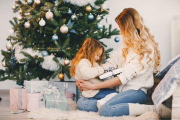 mommy and daughter wrapping gifts to put under the christmas tree