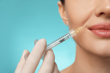 Beautiful woman getting facial injection on light blue background, closeup. Cosmetic surgery