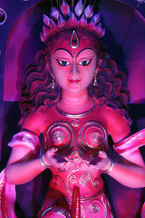 Goddess Durga idol at decorated Durga Puja pandal, shot at colored light, at Kolkata, West Bengal,...