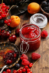 Jar of strawberry jam among summer and autumn fruits