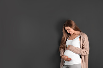 Young pregnant woman on grey background. Space for text