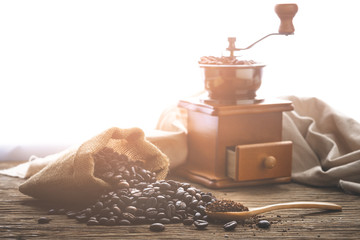 coffe bean with grinder and coffee in wooden spoon on wood table in morning light. - obrazy, fototapety, plakaty