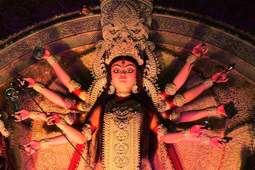 Goddess Durga idol at decorated Durga Puja pandal, shot at colored light, at Kolkata, West Bengal,...