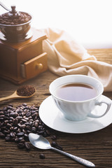 Close up coffe bean in wooden spoon and bag with grinder   on wood table in morning light.