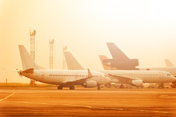 Many planes are standing at the airport at a beautiful sunset.