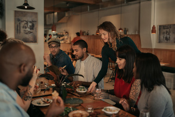 Waitress delivering food orders to a table of smiling customers