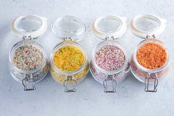 Four jars with different flavoured mixes of salt and spices. Himalayan and sea salt mixed with various peppers and herbs.