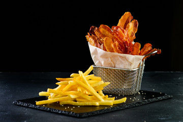 appetizer bacon chips and french fries on a dark background