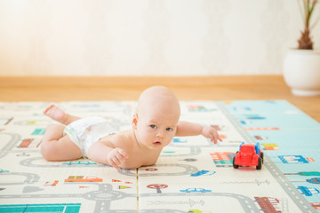 Newborn baby lying on his stomach on the playing Mat with city cars