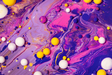 Acrylic paint balls abstract texture. Purple, blue and yellow liquids mix. Creative multicolor...