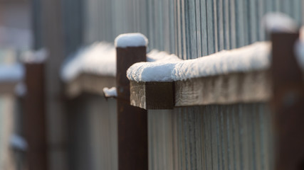 The fence near the house is covered with snow in the winter