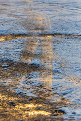 A frozen puddle covered with snow in the rays of the dawn of the sun in winter