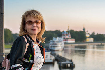 Fototapeta premium Portrait of an attractive woman against the background of the ancient city and the ships standing at the pier.