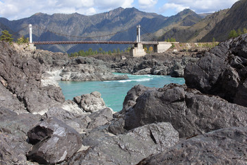 Fototapeta na wymiar Automobile bridge over the mountain river Katun. The rocks are gray. Turquoise water.