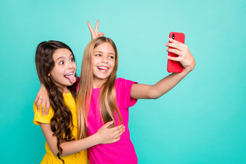 Photo of two cute excited nice brunette funky funny blonde model trendy people girls wearing pink yellow t-shirts recording video call while isolated with teal background