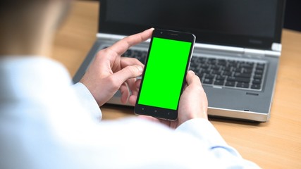Businessman in office scrolling mobile green screen cell phone pre-keyed place