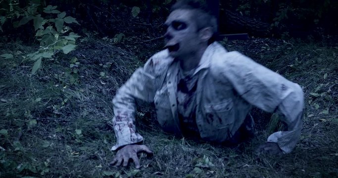 Zombie climbs out of the grave in the night cemetery. Halloween. Horror.