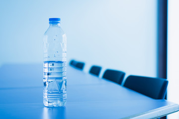 Drinking water bottle in meeting room, selective focus.