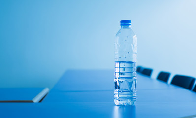 Drinking water bottle in meeting room, selective focus.
