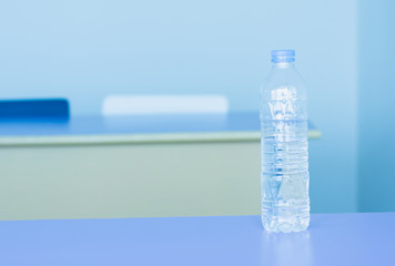 Drinking water bottle in meeting room, selective focus.