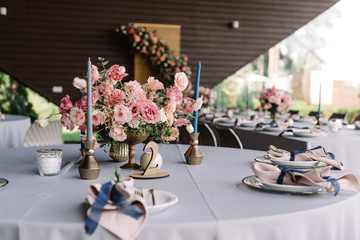 Holiday table adorns the table for guests. Stylish wedding flowers in a golden vase