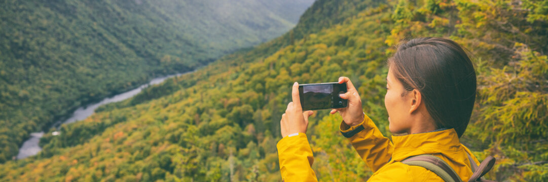 Travel hike woman hiker taking photo with phone of landscape of trail hiking in Quebec autumn foliage background panoramic banner. Canada fall camping lifestyle.