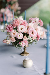 A stylish composition of fresh flowers in an antique vase and a small, nice candlestick.