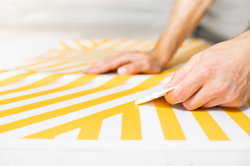 Adhesive foil wrapping. The man peels off the adhesive foil from the sheet