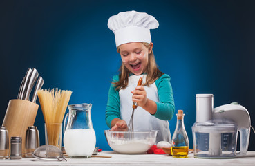 Kid Chef prepares a delicious dish on a blue background.studio portrait