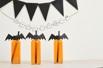 Decorated cocktail bottles with paper bats attached to straws at Halloween party
