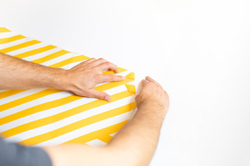 Sticking with foil. The man peels off the adhesive foil from the sheet