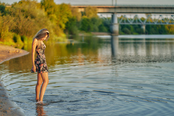teen girl walks along the beach in a short summer dress. copy space