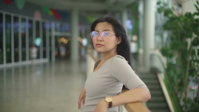 Young Asian Woman in glasses standing in front of building. Slow motion