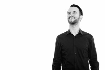 Studio shot of happy young man smiling and thinking while looking up