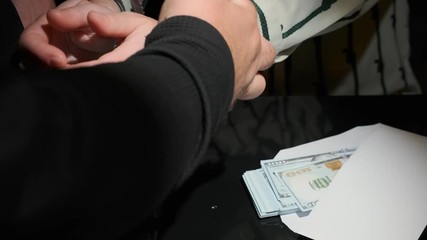 Handcuffs are put on female hands on black background close-up. Concept of arrest of official for bribe in workplace.