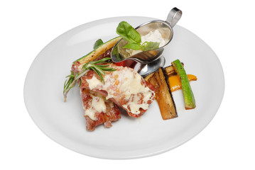 Steak with vegetables and white sauce on white plate on white isolated background