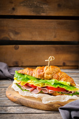 Fresh croissant sandwich with ham, cheese, lettuce and tomato