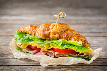 Fresh croissant sandwich with ham, cheese, lettuce and tomato