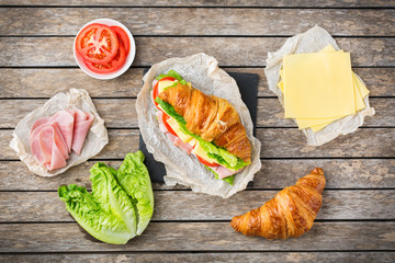 Fresh croissant sandwich with ham, cheese, lettuce and tomato