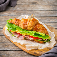 Fresh croissant sandwich with ham, cheese, lettuce and tomato