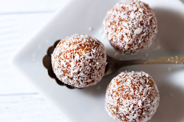 mouth-watering energy balls on a white square plate with a spoon.