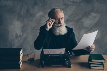 Portrait of his he nice attractive bearded focused concentrated gray-haired professional expert creative publisher reading news life story article essay over concrete wall background