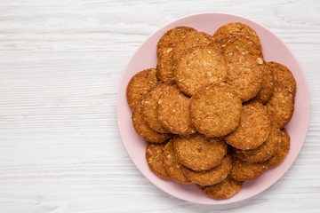 Cereal cookies on a pink plate on a white wooden background, top view. Flat lay, overhead, from above. Space for text.