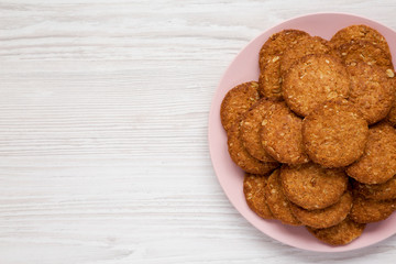 Cereal cookies on a pink plate on a white wooden background, top view. Flat lay, overhead, from above. Copy space.
