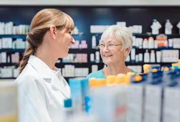 Obraz premium Chemist and customer standing in pharmacy between the shelves