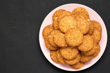 Cereal cookies on a pink plate on a black background, top view. Flat lay, overhead, from above. Copy space.