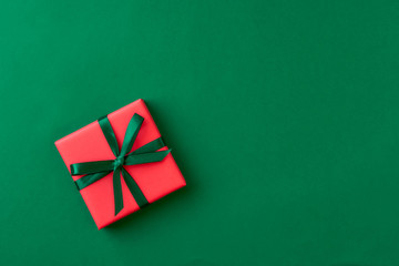 Red gift box on green background. Christmas card. Flat lay.Top view with space for text	