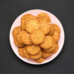 Cereal cookies on a pink plate on a black background, view from above. Flat lay, top view, overhead. Close-up.